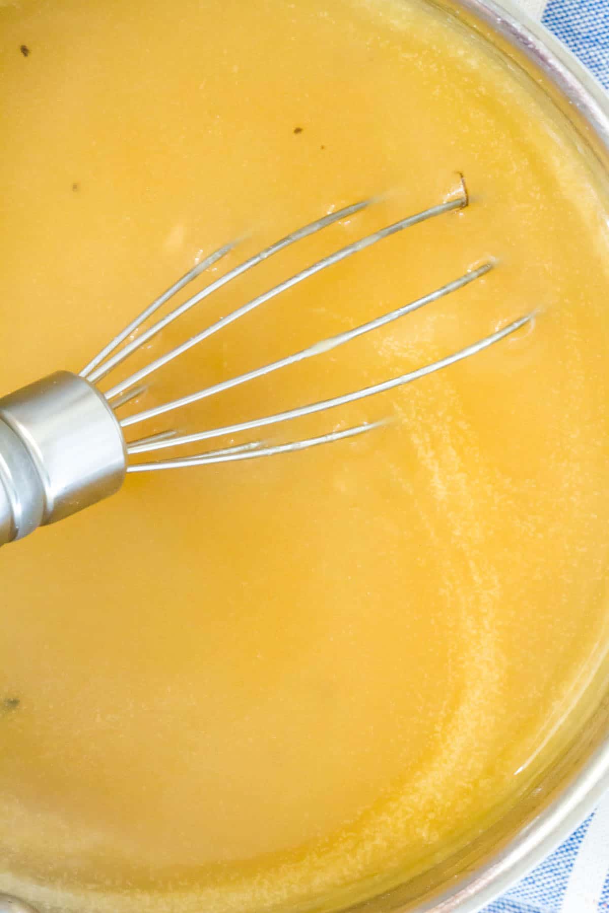 close up on a pot of gravy with a whisk