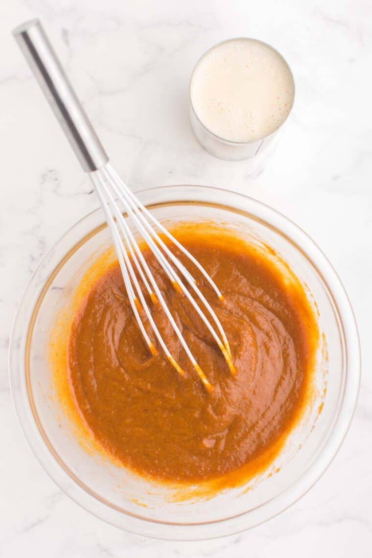 the pumpkin mixture in a bowl with a whisk next to a can of evaporated milk