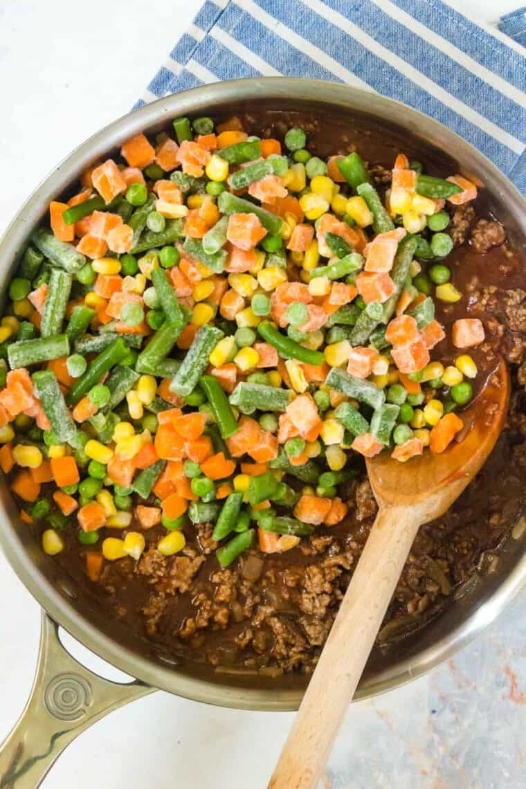 frozen vegetables added on top of the ground beef mixture in the pan