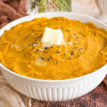 bowl of mashed sweet potatoes with butter and a sprinkle of thyme