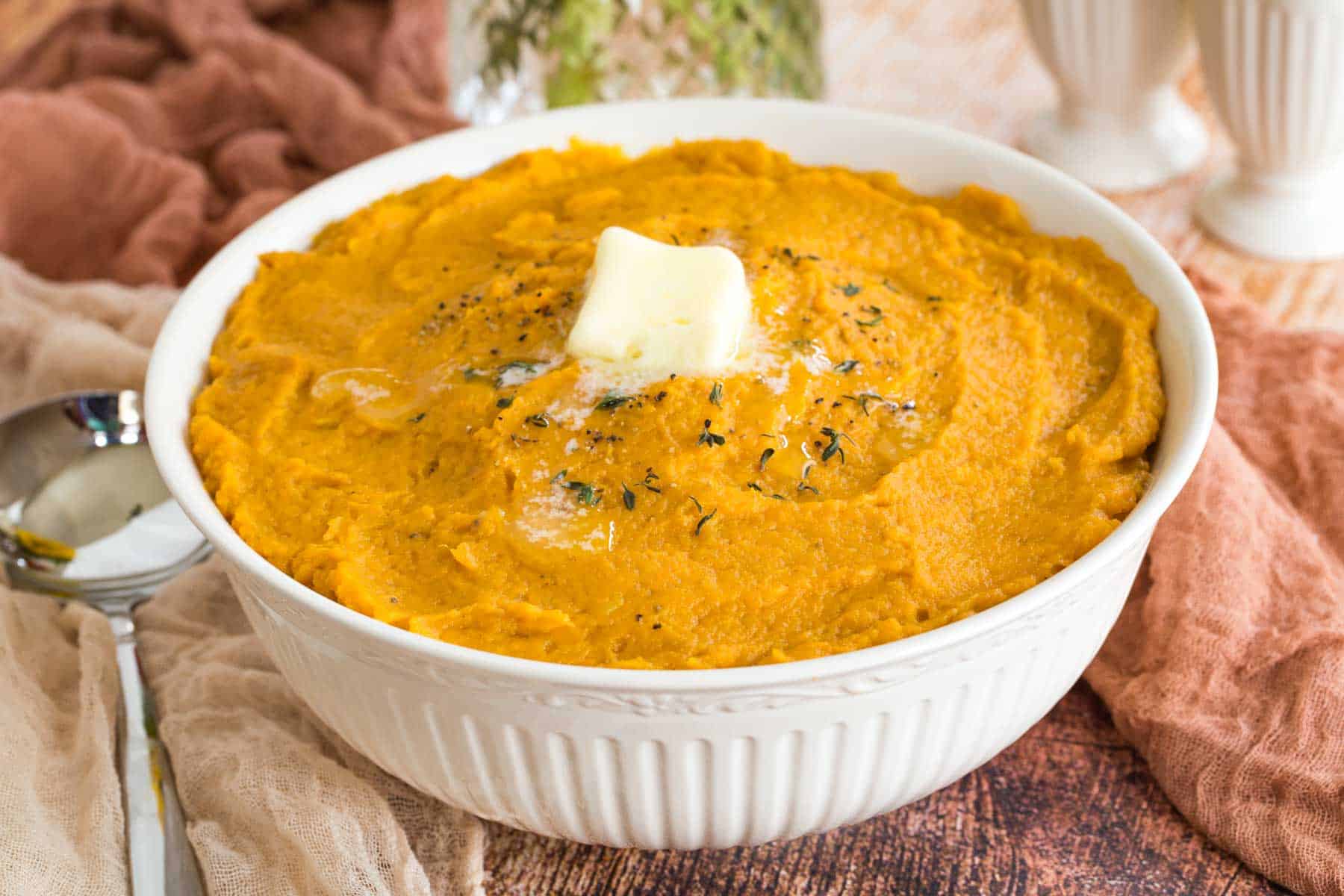 bowl of mashed sweet potatoes with butter and a sprinkle of thyme