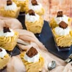 a bunch of mini pumpkin mousse parfaits scattered on slate platters and gauzy cloth napkins