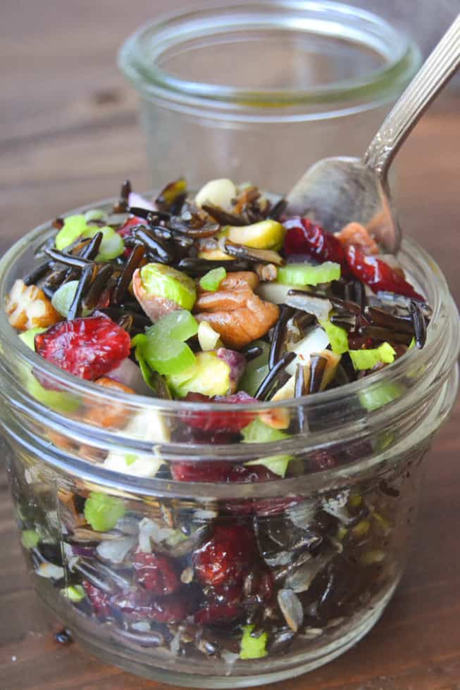 Vegan wild rice salad with cranberries and nuts in a glass dish.