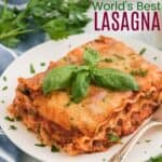 slice of lasagna on a plate with a sprig of basil leaves on top