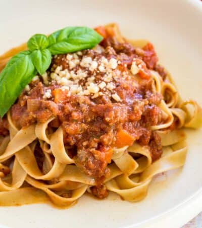 white plate of pasta with bolognese sauce