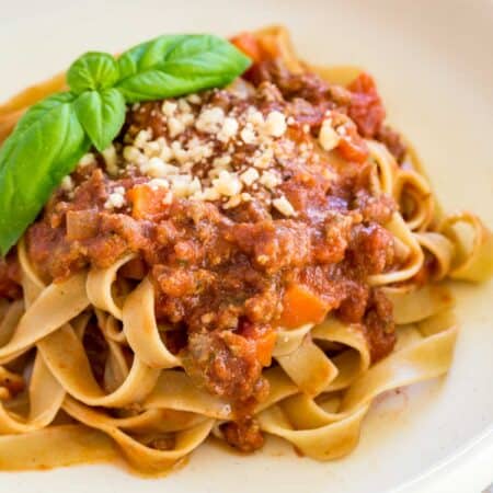 white plate of pasta with bolognese sauce