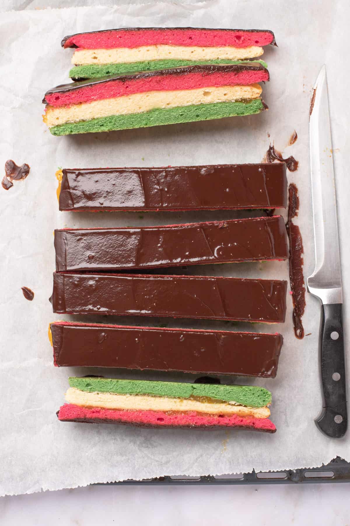 slicing chocolate-topped rainbow cookies