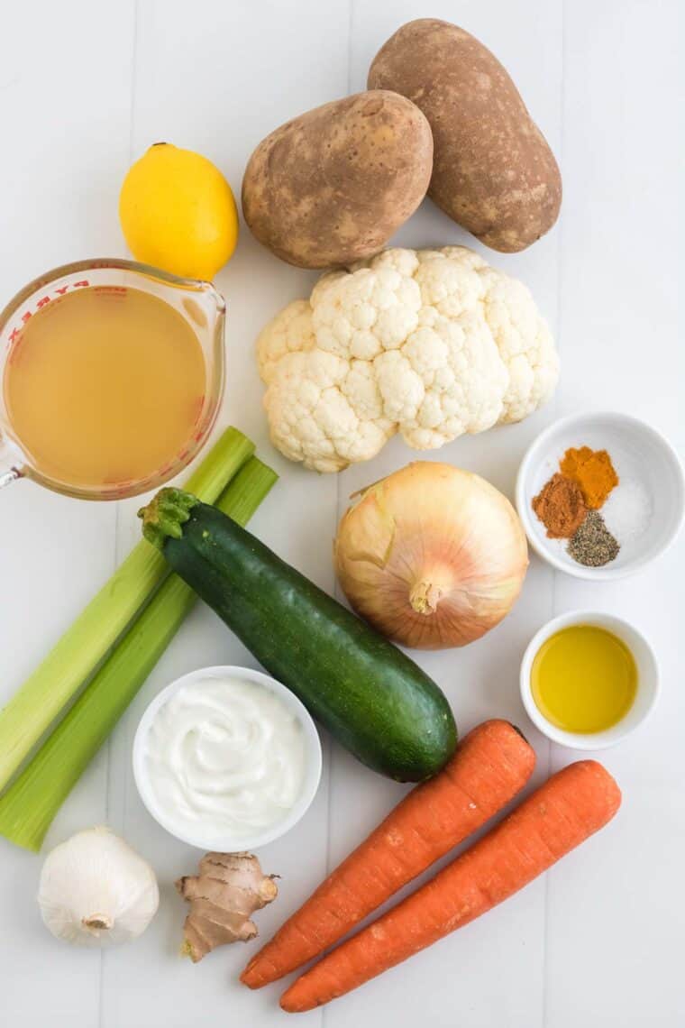 vegetables, spices, and broth on a table to make vegetable soup