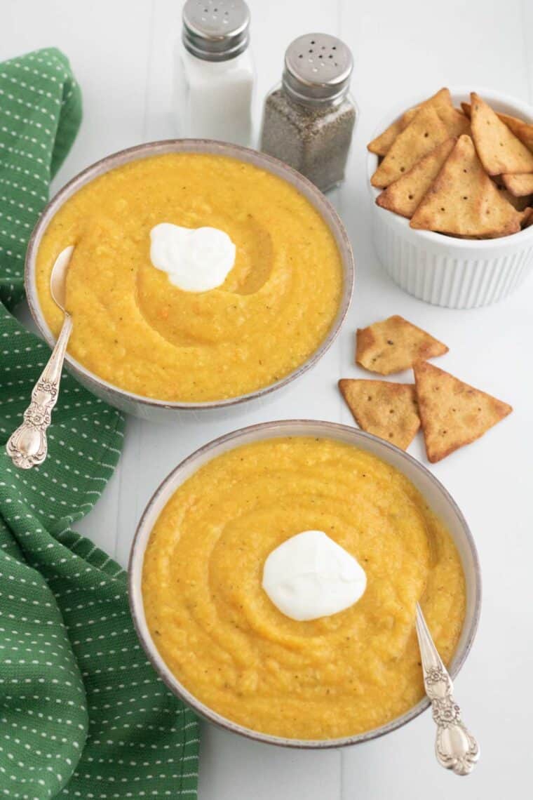 two bowls of pureed vegetable soup with dollops of Greek yogurt on top