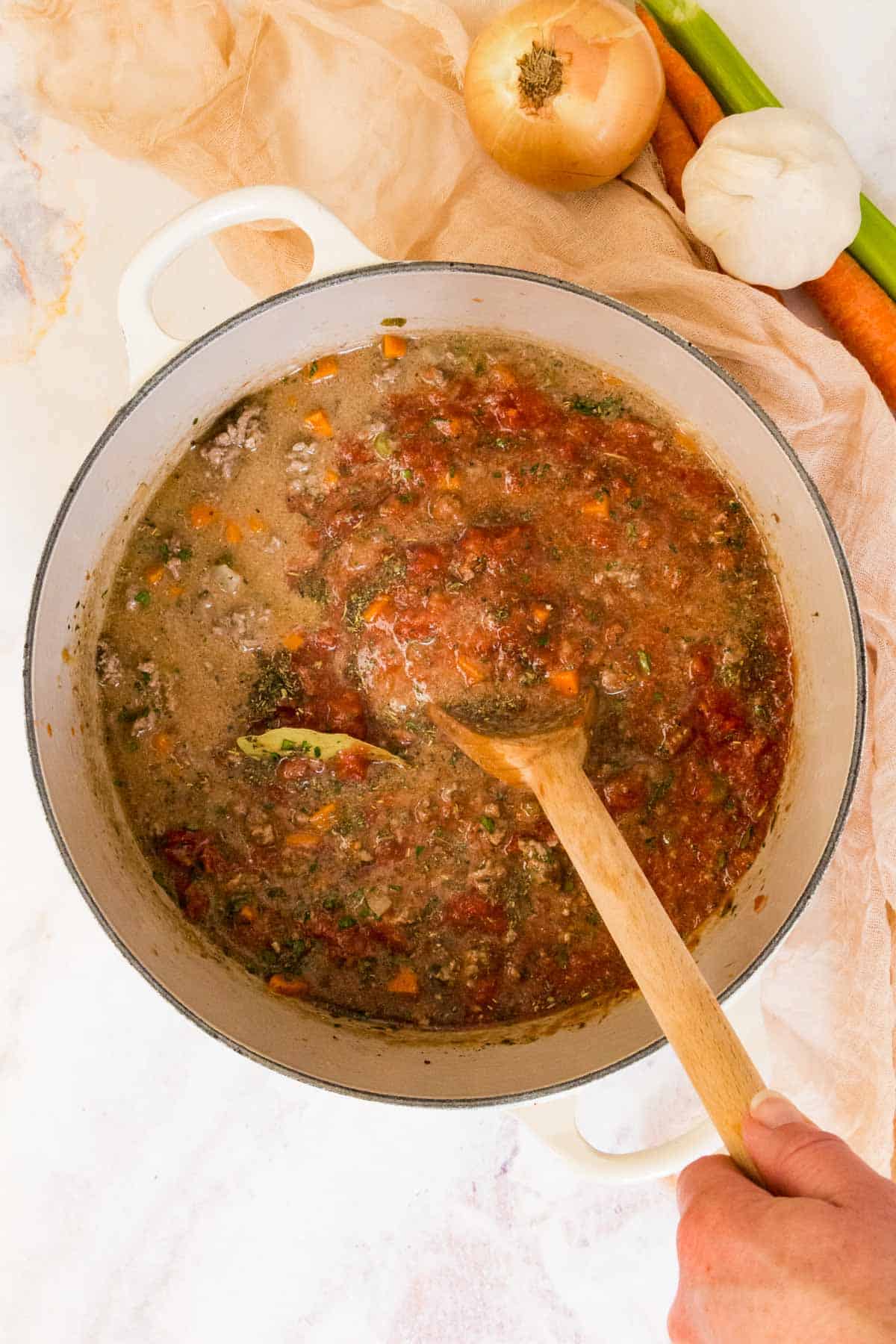 stirring bolognese sauce in a pot