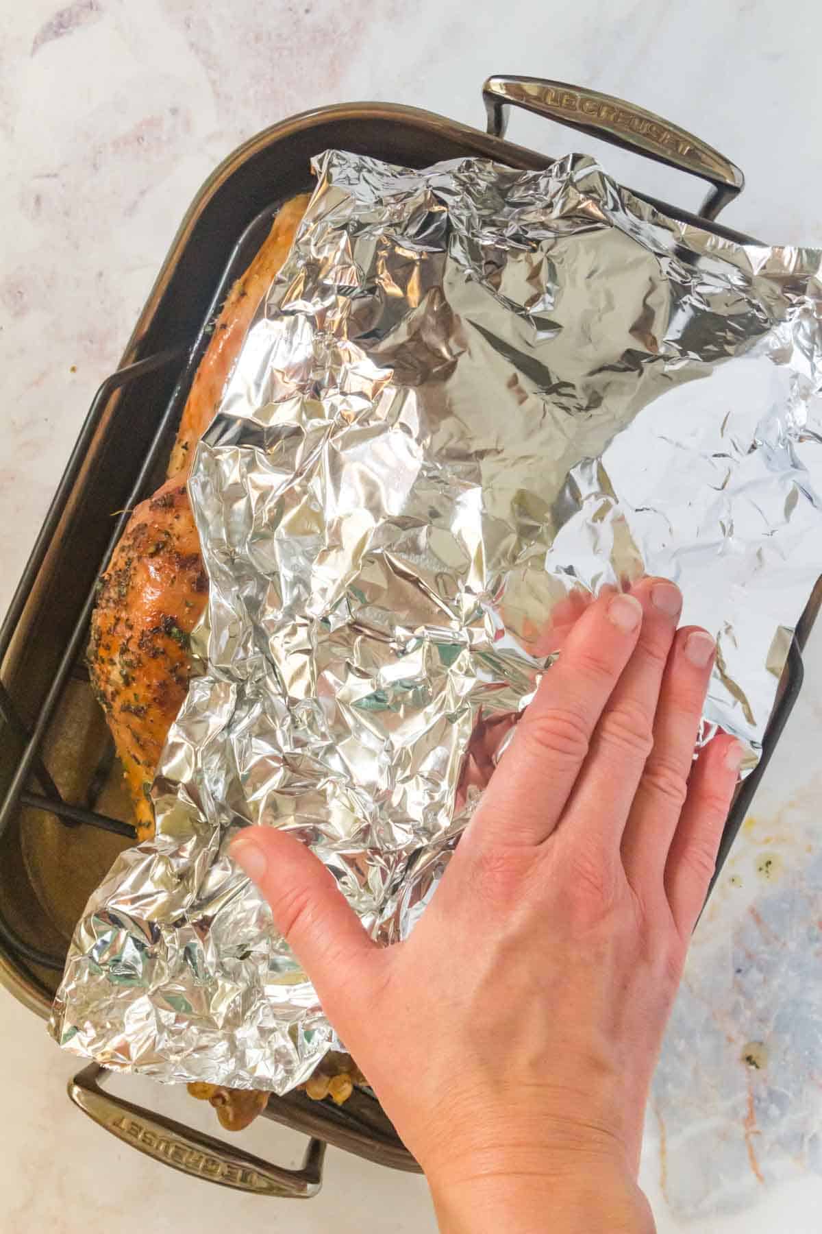 placing a sheet of aluminum foil over the partially roasted turkey