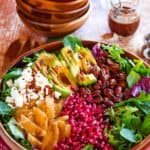 winter salad in a large wooden bowl with orange slices, pomegranate arils, and more toppings