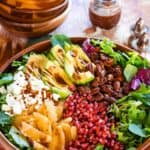 winter salad with fruit, nuts, and feta in a wooden bowl