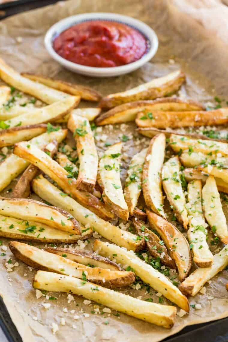 crispy golden french fries on a baking sheet sprinkled with parmesan and parsley