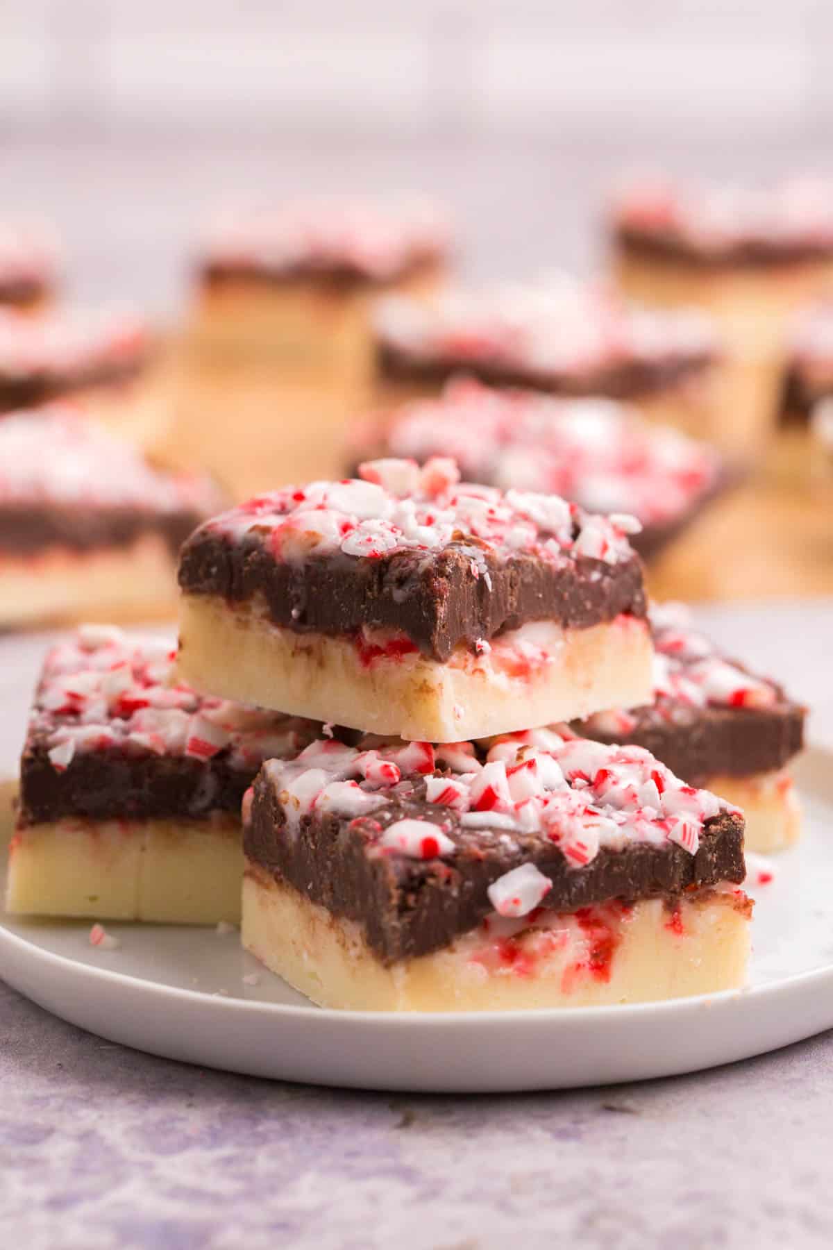 four squares of peppermint fudge with layers of white and dark chocolate on a white plate