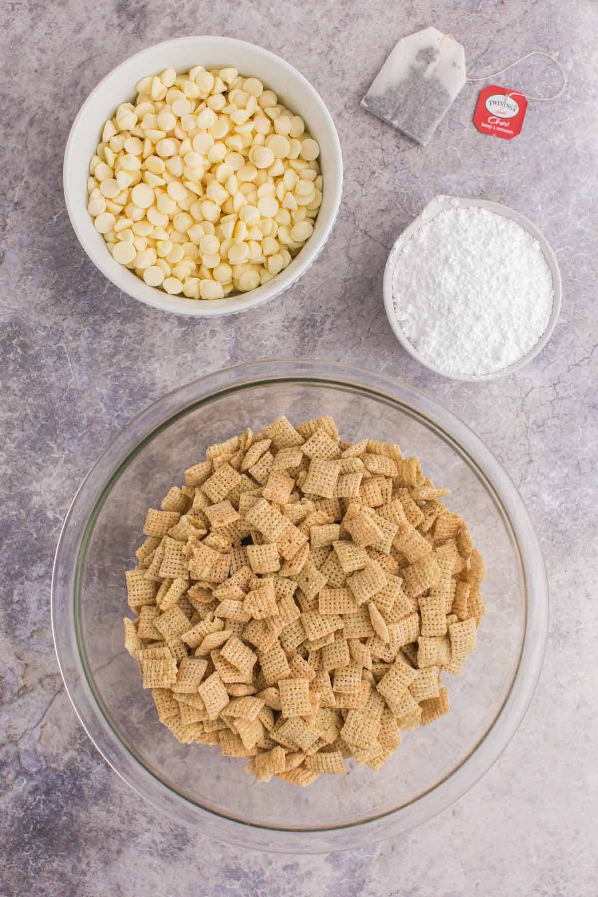 bowls of chex cereal, white chocolate chips, and powdered sugar and a chai tea bag