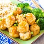 Saucy Asian chicken meatballs on a green plate with rice and broccoli