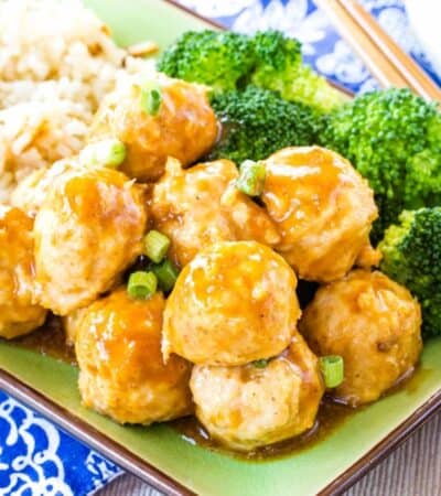 Saucy Asian chicken meatballs on a green plate with rice and broccoli