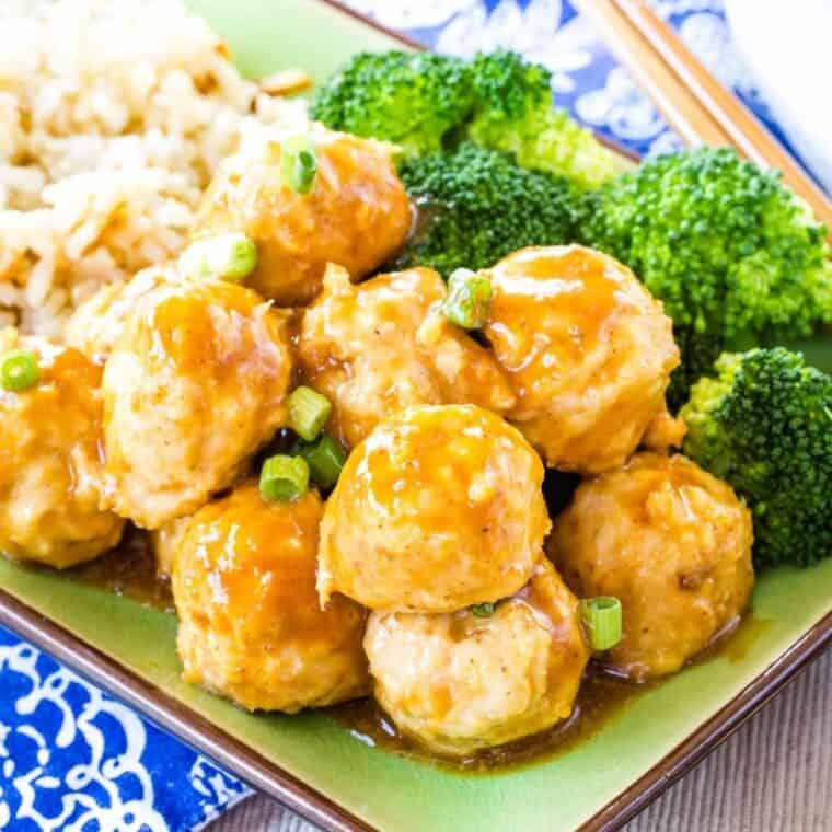 Saucy Asian chicken meatballs on a green plate with rice and broccoli