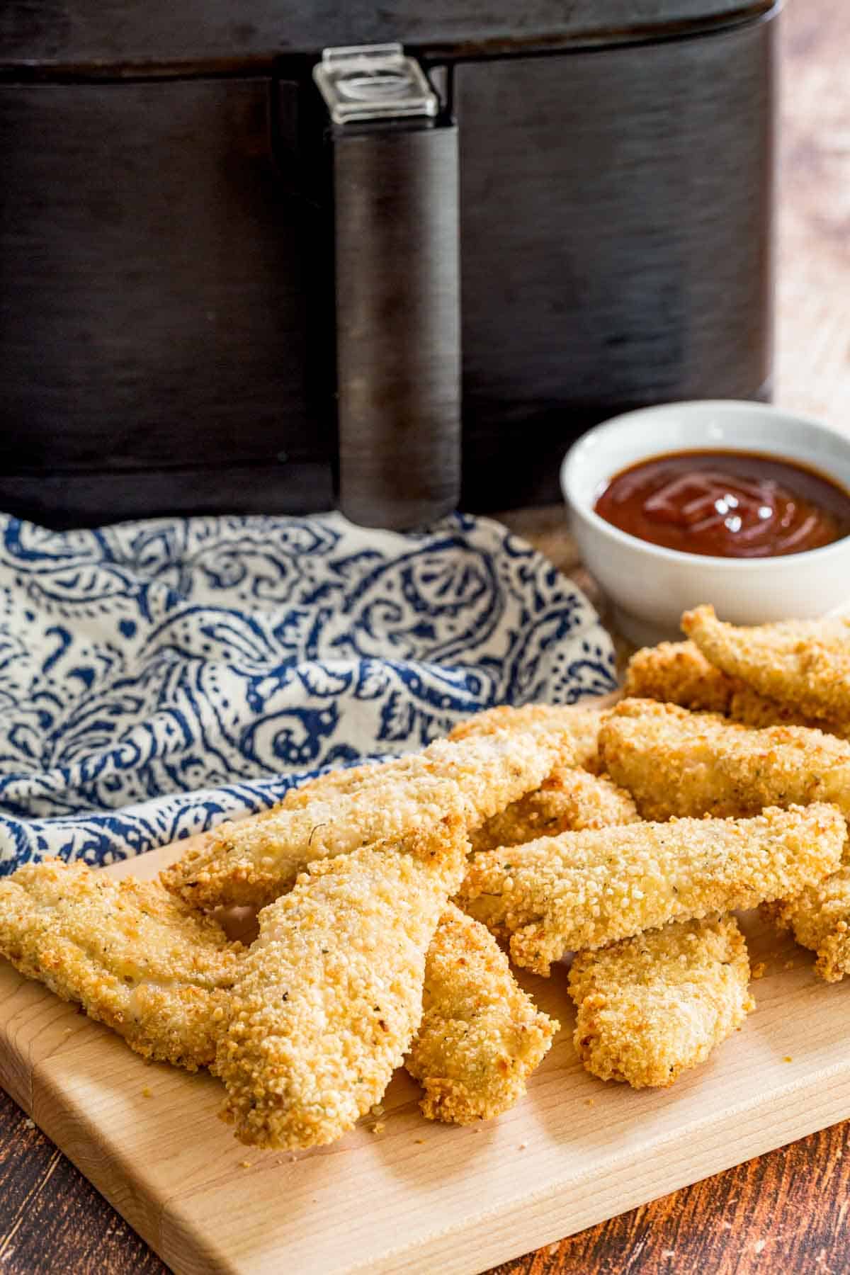 Air fryer chicken tenders served next to a bowl of BBQ sauce for dipping.