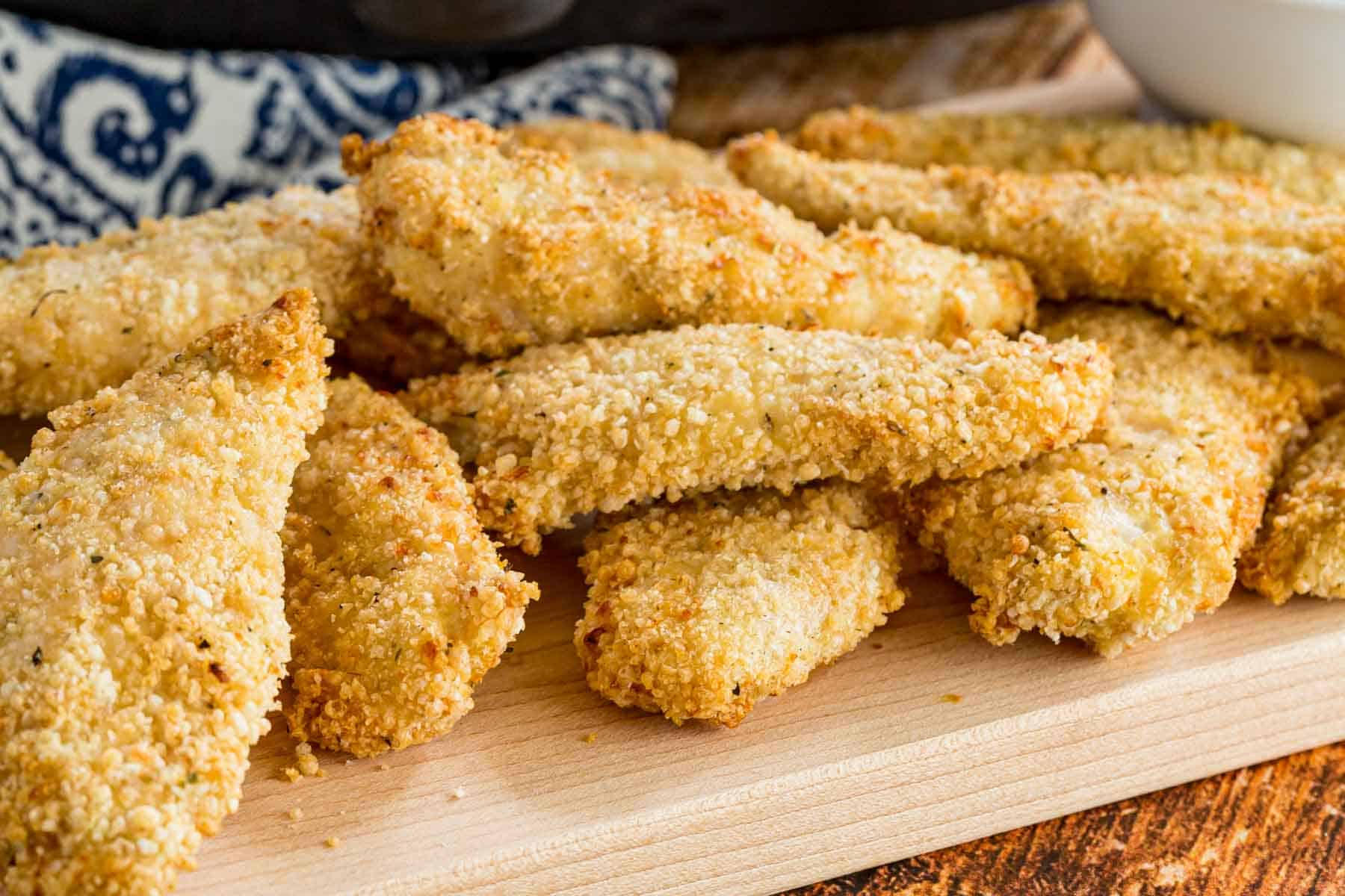 Air fryer chicken tenders served next to a bowl of BBQ sauce for dipping.