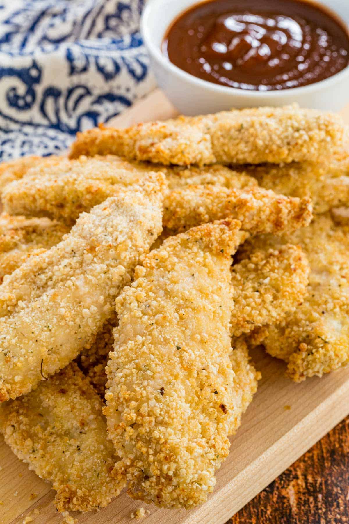 Air fryer chicken tenders served next to a bowl of BBQ sauce for dipping.