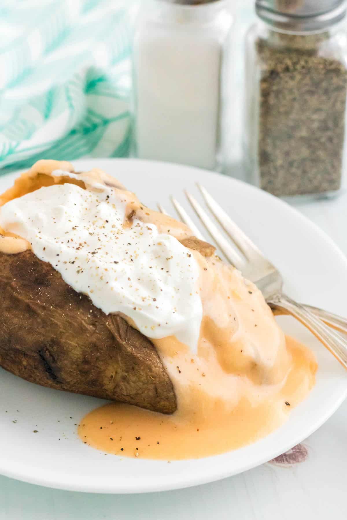 A fully loaded baked potato topped with gluten free cheese sauce and sour cream.