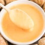 A spoon dipped in cheese sauce.