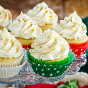 Eggnog cupcakes topped with a swirl of frosting on a glass platter.