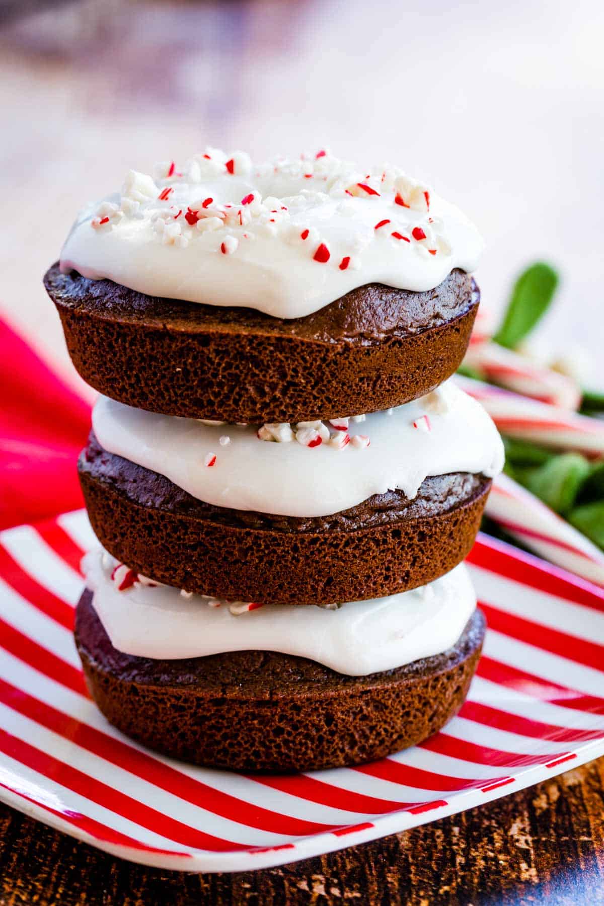 a stack of three gluten free peppermint chocolate donuts on a red and white plate