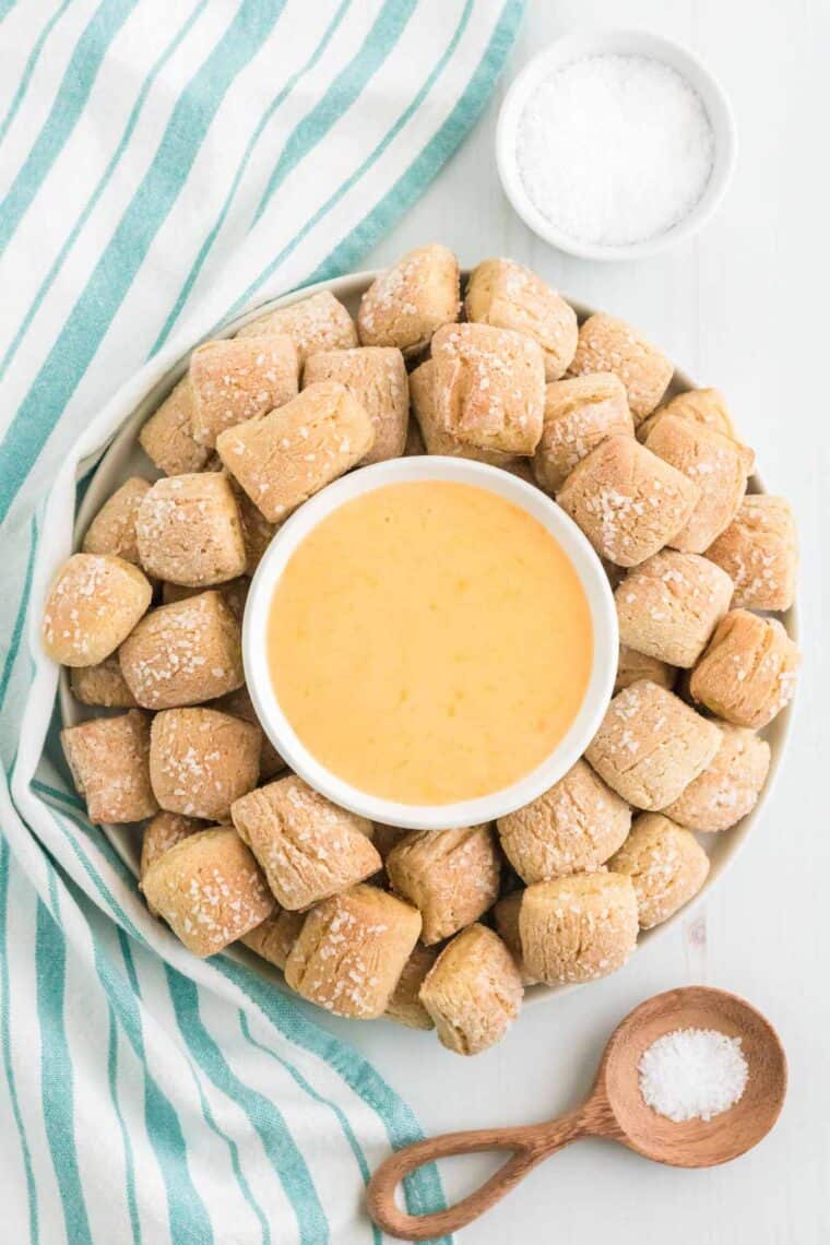 Gluten free pretzel nuggets arranged on a plate with a bowl of cheese sauce in the center.