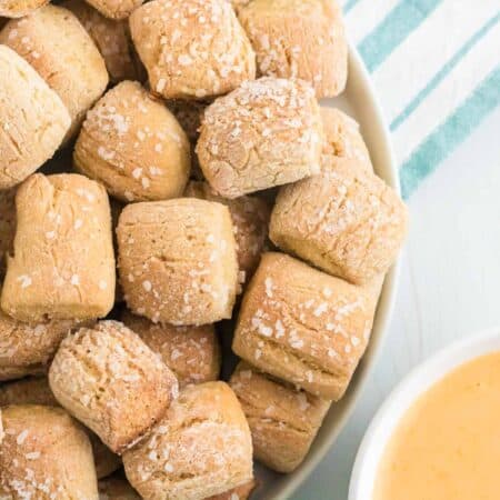 Gluten free pretzel bites on a plate next to cheese sauce.