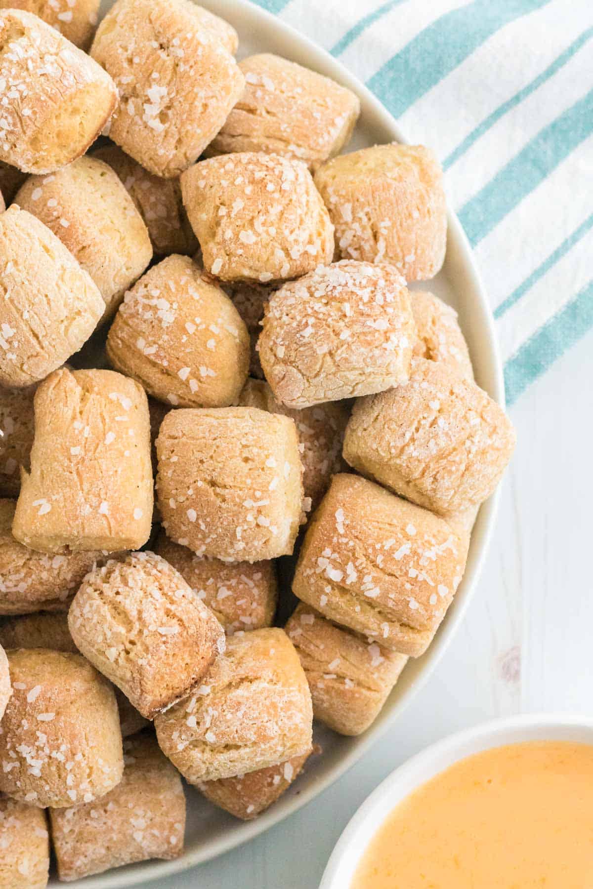 Gluten free pretzel bites on a plate next to cheese sauce.