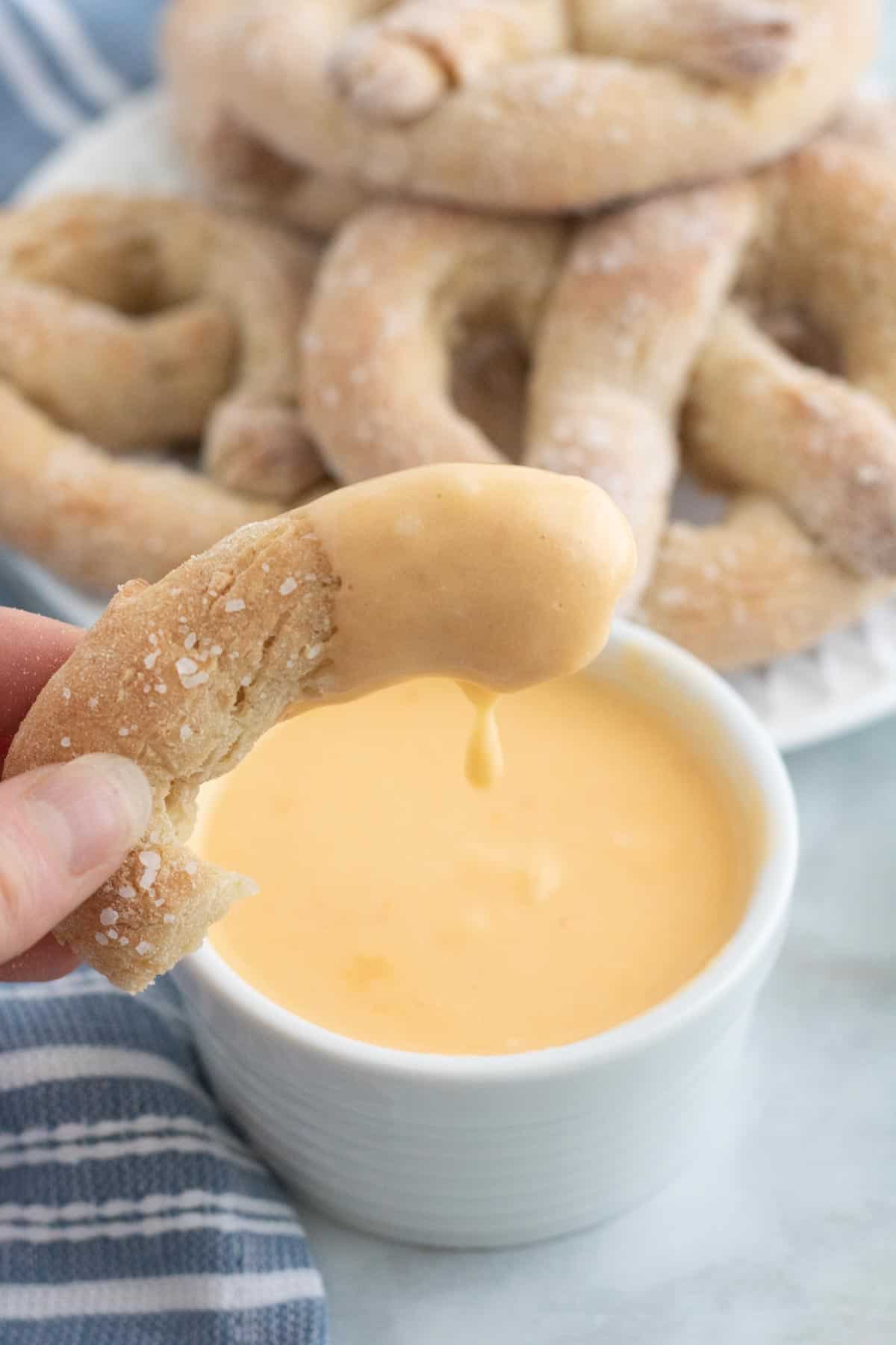 A piece of soft pretzel dipped in cheese sauce.