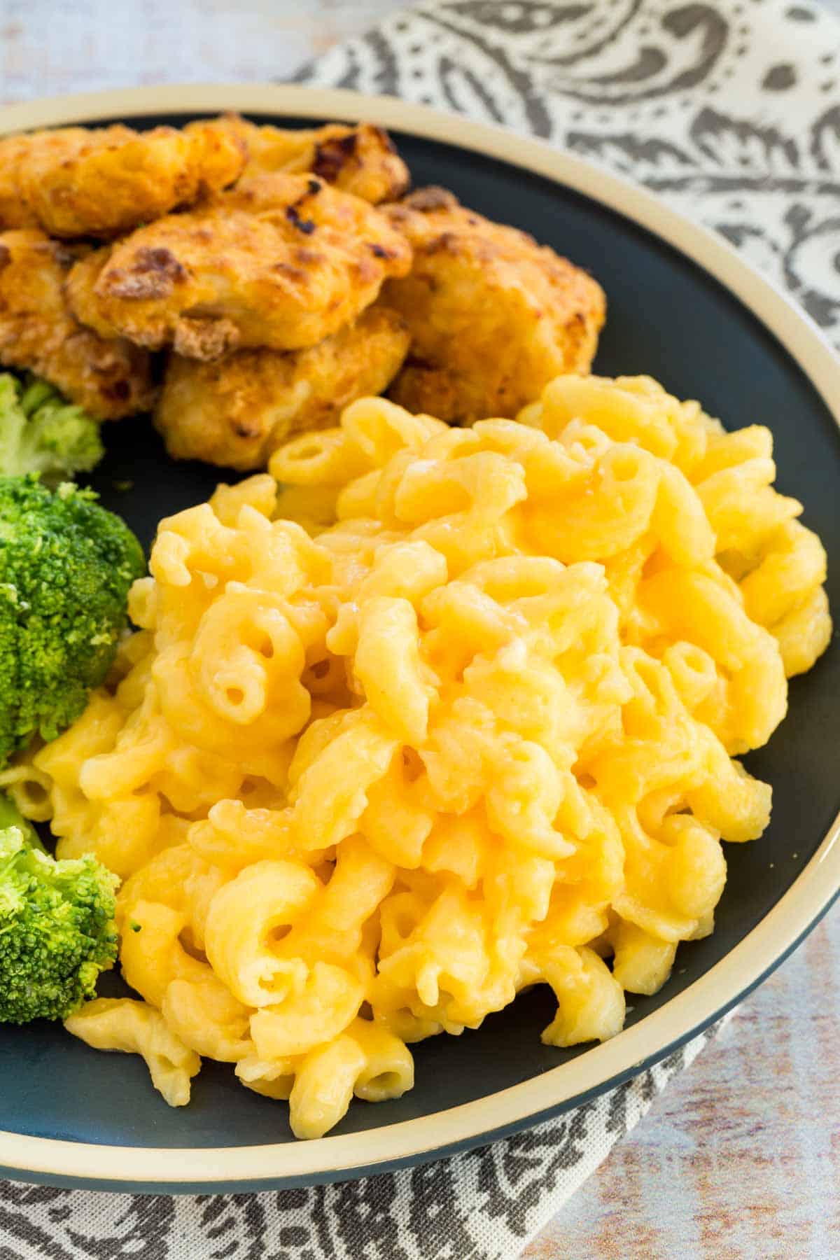 Stovetop mac and cheese served on a plater with broccoli and chicken.