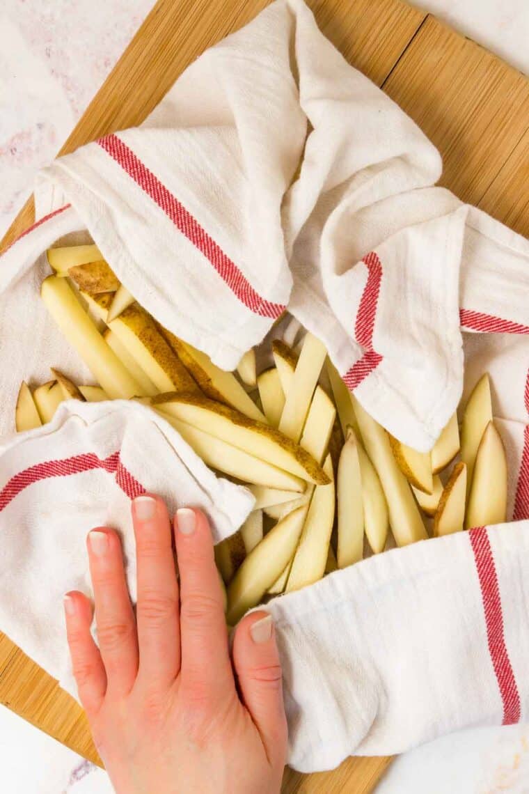 drying uncooked cut potatoes with a kitchen towel