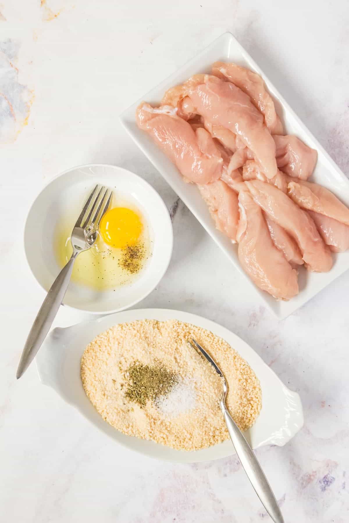 The ingredients for the coating for air fryer chicken tenders are combined in separate bowls.