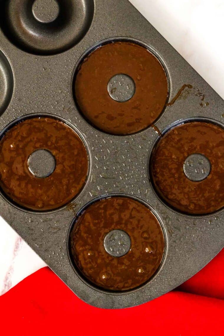 chocolate batter in the cavities of a donut pan