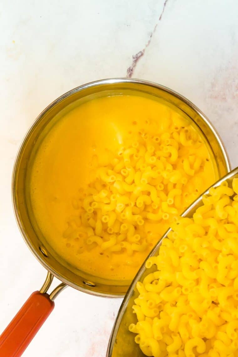Macaroni noodles are added to the pot with cheese sauce for stovetop mac and cheese.