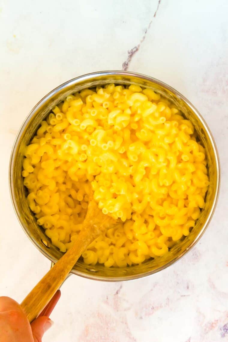 Noodles and cheese sauce is stirred together for gluten free stovetop mac and cheese.