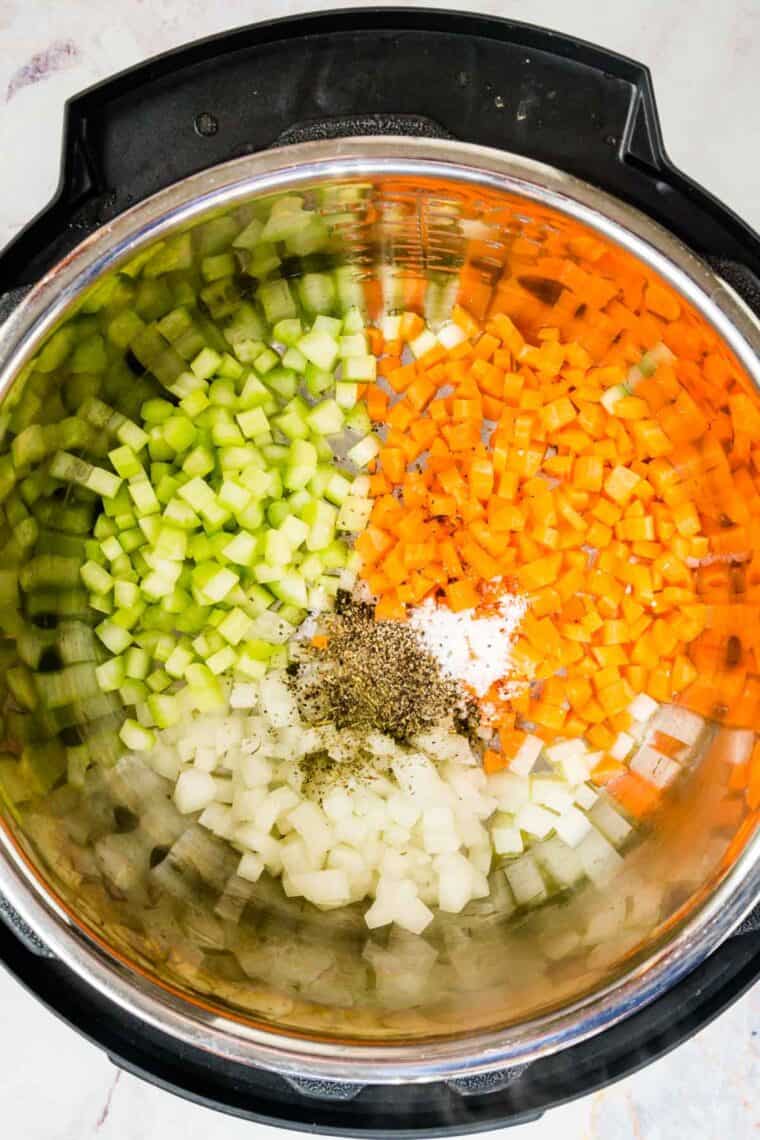 Seasoning is added into the Instant Pot with the diced carrots, celery, and onion.