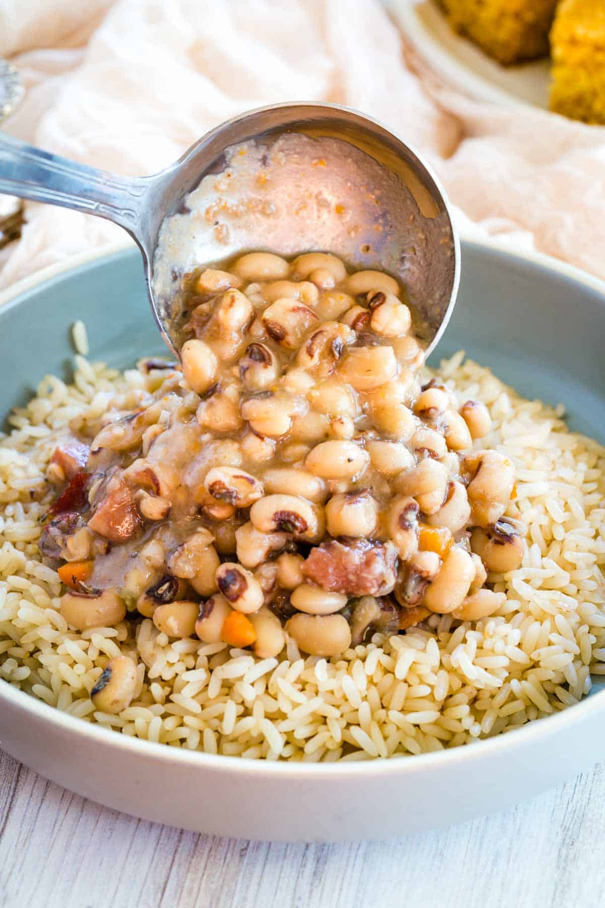 A ladle is used to serve black eyed peas over rice.