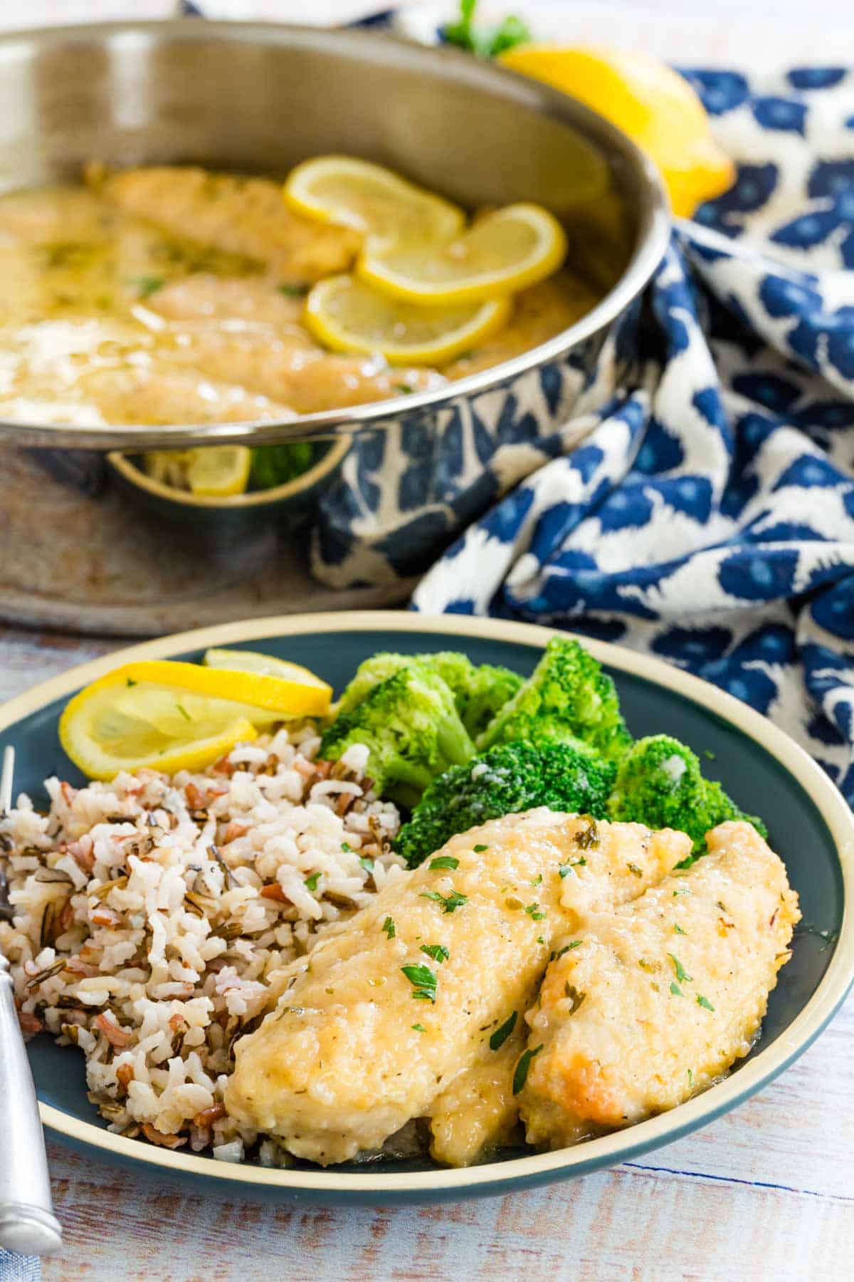 Three pieces of lemon chicken on a plate with wild rice and broccoli