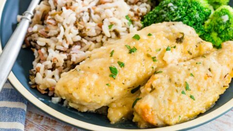 A close-up shot of skillet lemon chicken on a dinner plate along with rice and veggies