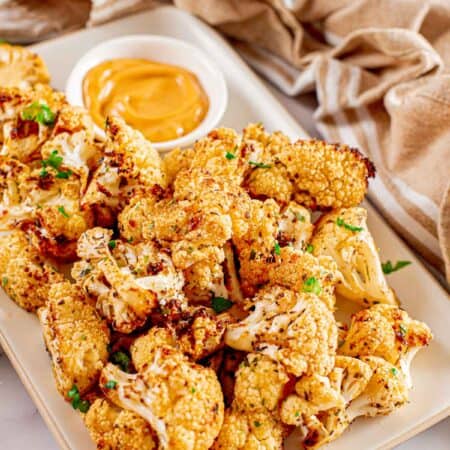 air fryer roasted cauliflower on a rectangular plate with a bowl of dipping sauce