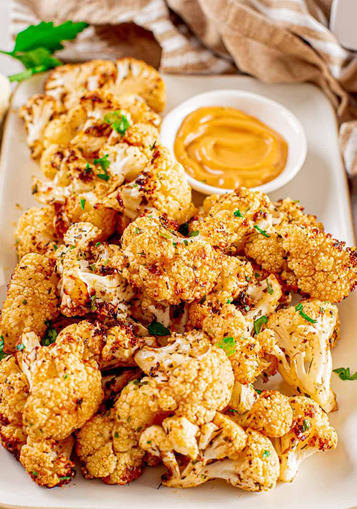 a pile of air fried cauliflower with a bowl of dip