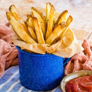french fries in a blue mug lined with parchment paper