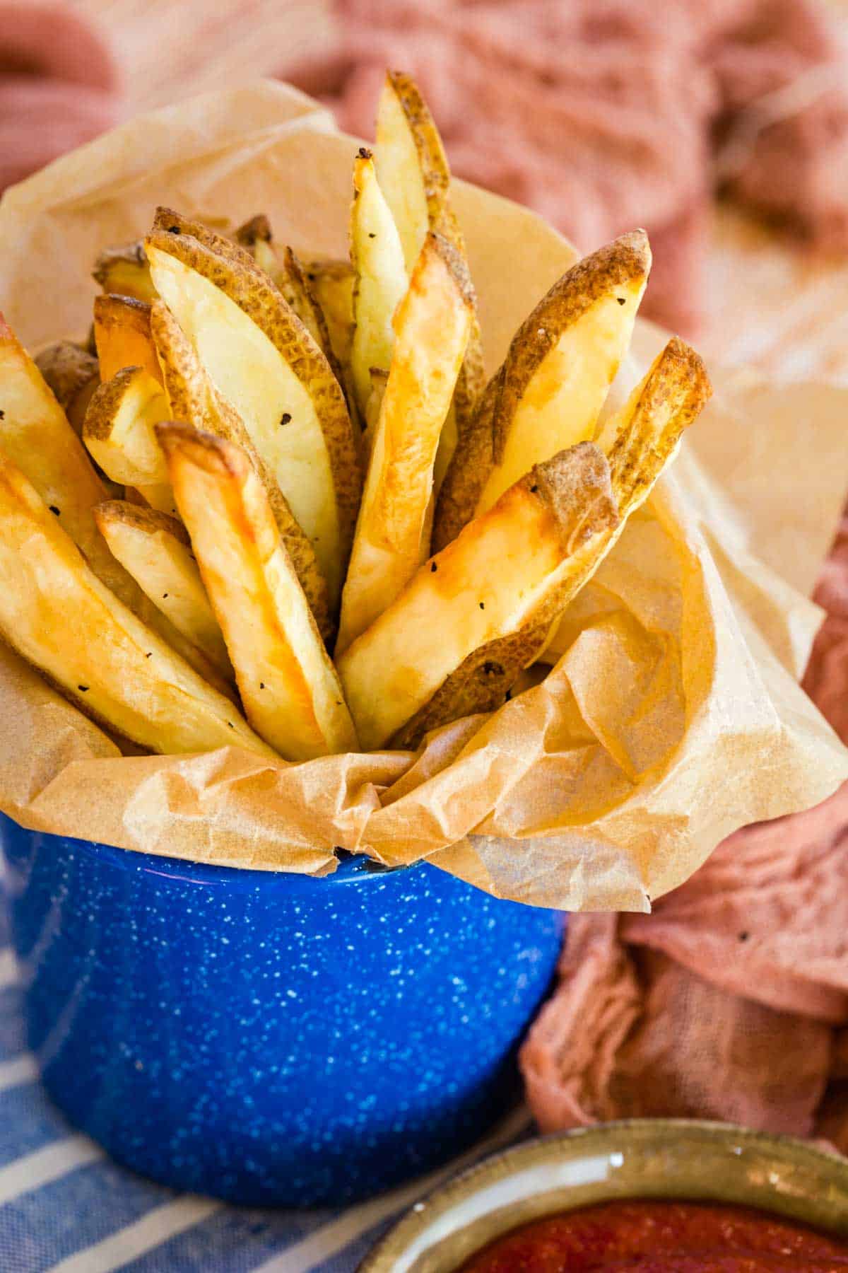 air fryer french fries peeking out of the top of a cup lined with parchment paper