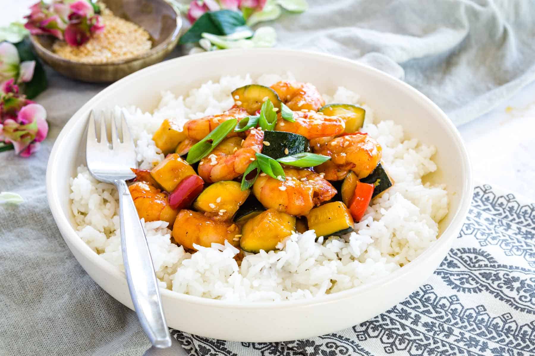 a bowl of bourbon shrimp and veggies served over white rice