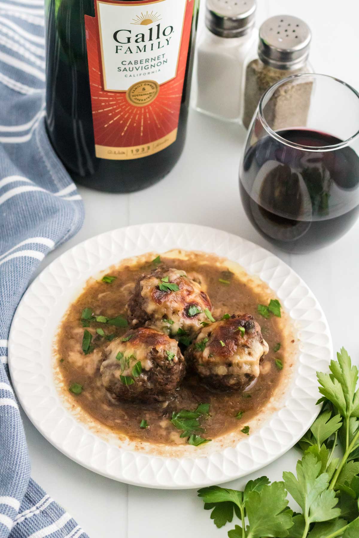 French onion meatballs served next to a glass of red wine.